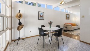 A modern interior with a round dining table, black chairs, a hat stand, and a sofa in a bright room with large windows. - Las Hermanas - Close to Sul ROss, Kokernot Park, Downtown (Alpine)