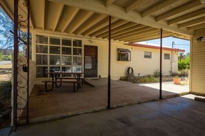 Une terrasse couverte avec une table de pique-nique et une fenêtre donnant sur un quartier résidentiel.