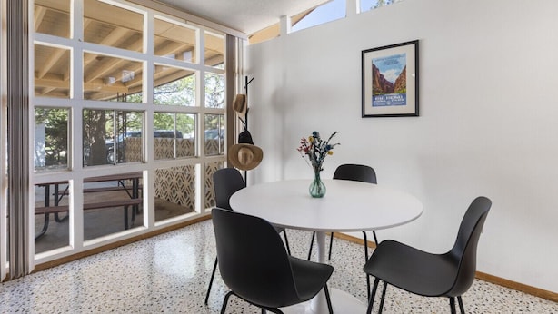 A dining area with a round table, black chairs, a vase with flowers, and a framed picture on the wall. - Las Hermanas - Close to Sul ROss, Kokernot Park, Downtown (Alpine)