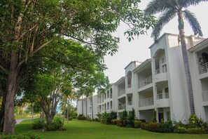 A multi-story hotel with a central courtyard, surrounded by lush greenery and palm trees. - New Green Bay I Condos Golf View (Nuevo Nayarit)