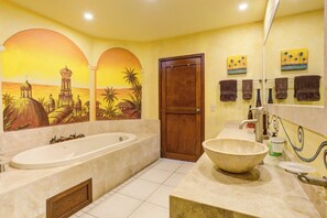 A bathroom with a large bathtub, a large sink, and a wooden door.