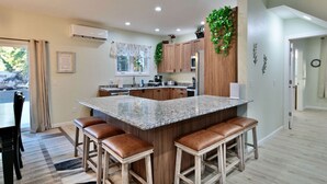 Una cucina moderna con un'isola in granito, sgabelli da bar in legno e vista sull'esterno.