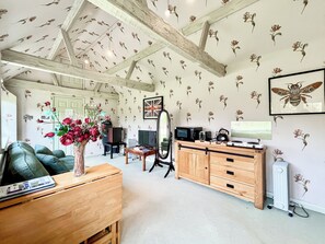 A room with a wooden cabinet, a television, a radiator, and a floral wallpaper pattern.