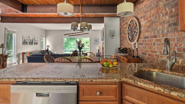 A modern kitchen with granite countertops, a dishwasher, and a brick backsplash.