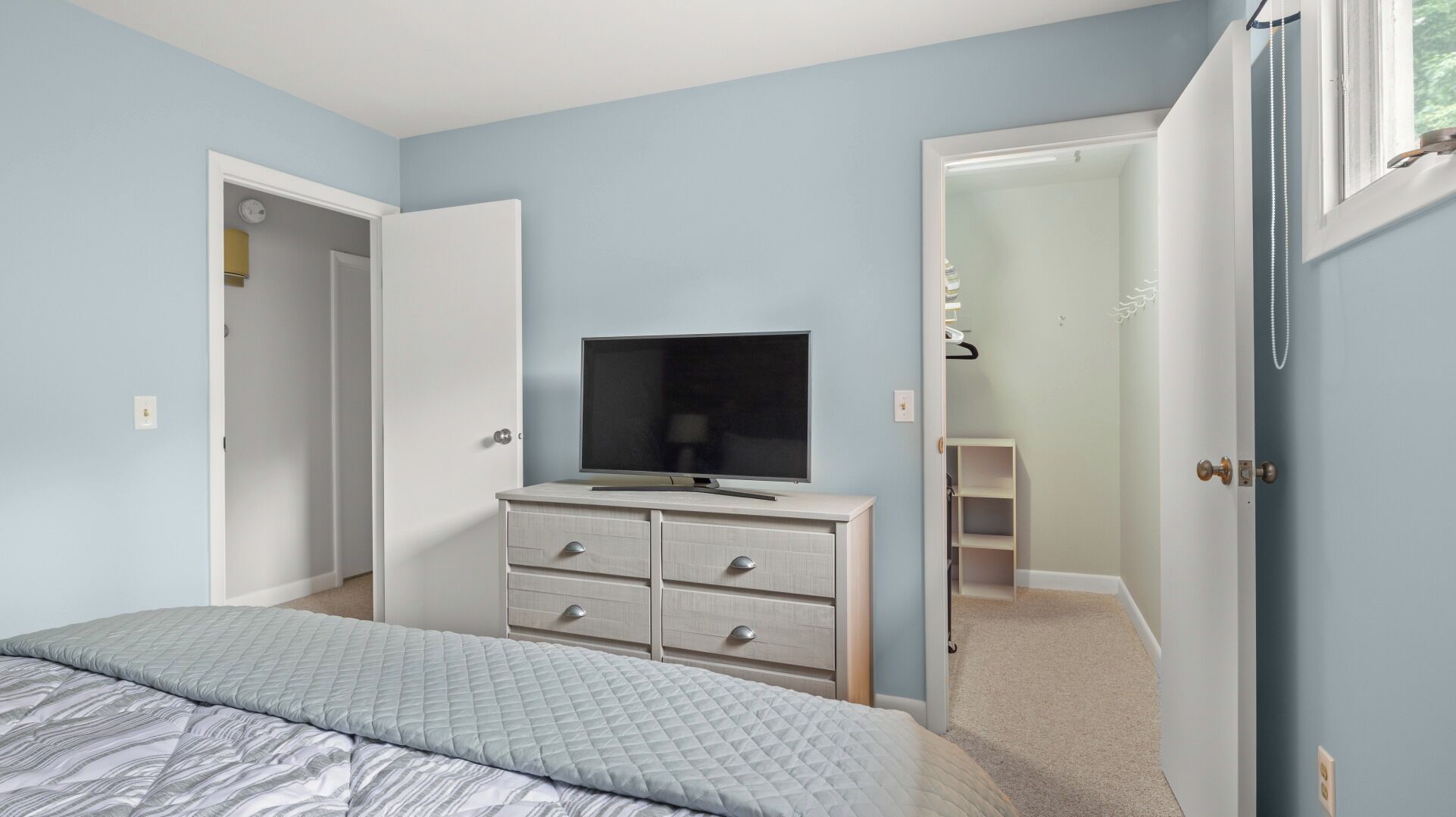 Une chambre à coucher comprenant un lit, une commode, un téléviseur et un placard.