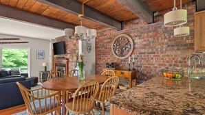 A modern kitchen with a brick wall, wooden ceiling, and granite countertop.