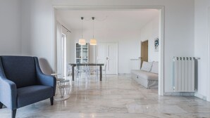 A modern living room with a sofa, a dining table with chairs, and a kitchen area in the background. - Europa Landscape by Wonderful Italy (Catania)