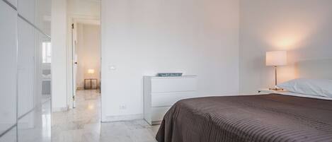 Une chambre moderne avec un grand lit, une table de chevet avec une lampe et une armoire.