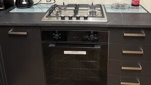 Une cuisine moderne équipée d’une cuisinière à gaz, d’un four et d’une bouilloire posée sur le plan de travail.