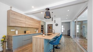 A modern kitchen with a wooden island, bar stools, and a large window. - Villa Pinus with Pool, Game Room, Garden (Cervar Porat)