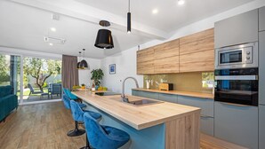 A modern kitchen with a wooden island, bar stools, and stainless steel appliances. - Villa Pinus with Pool, Game Room, Garden (Cervar Porat)