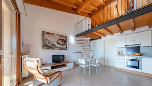 A modern kitchen with white cabinets, a dining area with a table and chairs, a sofa, and a painting on the wall.