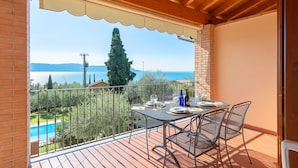 A balcony with a table set for dining, overlooking a pool and a mountainous landscape.