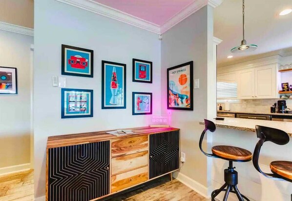 A modern kitchen with white cabinets, a wooden countertop, and a bar area with stools.