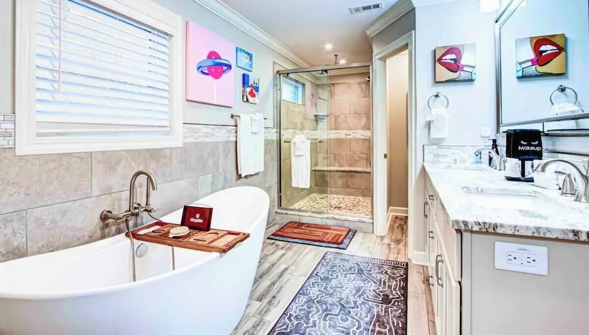 Une salle de bain moderne dotée d’une baignoire sur pieds, d’une douche à parois de verre et d’un meuble-lavabo avec un espace dédié au maquillage.