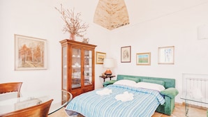 A bedroom with a bed, a wooden cabinet, a glass table, and a chair. - Appartamento fronte mare a Ospedaletti by Wonderful Italy (Ospedaletti)