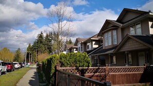 Une rue résidentielle bordée de maisons, avec des voitures garées et un ciel dégagé.
