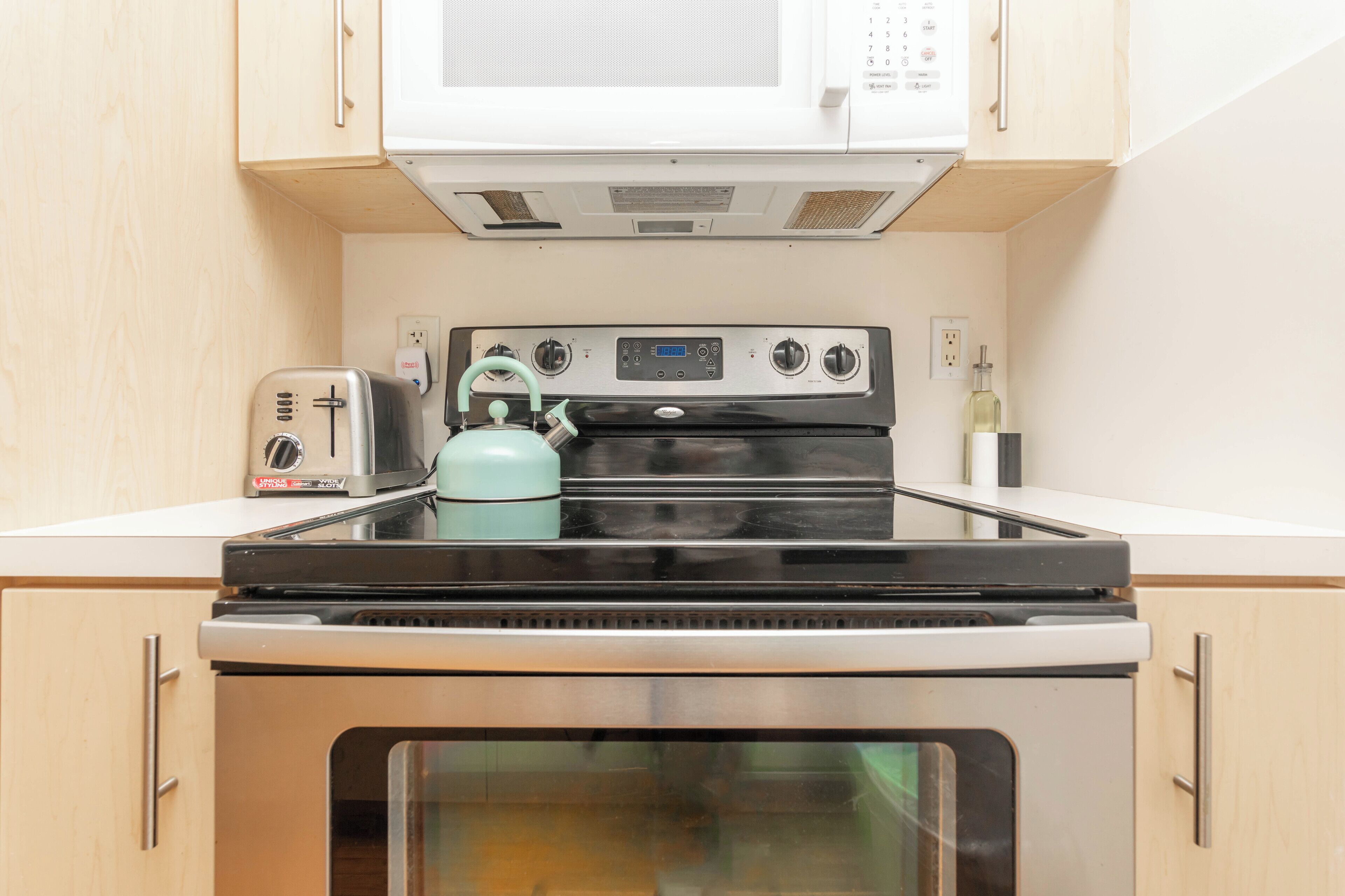 A kitchen with a stove, oven, microwave, and a toaster.