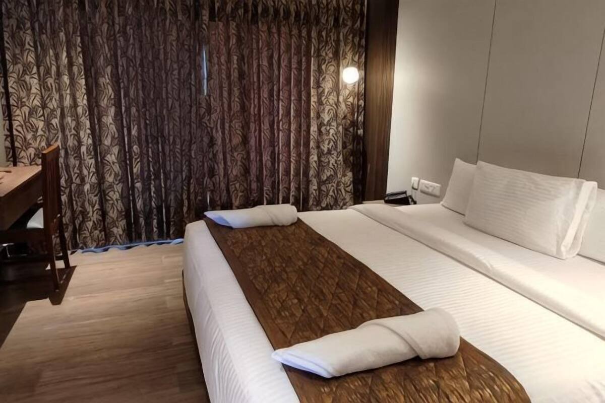 A hotel room with a bed, a desk, and a curtain.