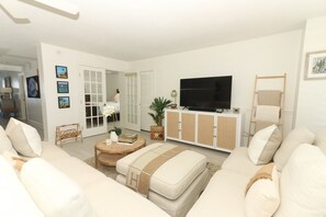 Relax in this stylish living room with a large flat-screen TV, comfortable sofa, and wicker coffee table.