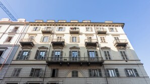 A multi-story building with a classic architectural style, featuring balconies, arched windows, and a ground-level entrance with a wooden door. - Casa Juliette by Wonderful Italy (Turin)
