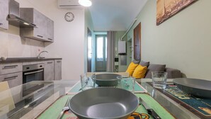 A modern kitchen with a dining area, a sofa with yellow cushions, and a painting on the wall. - Casa Juliette by Wonderful Italy (Turin)