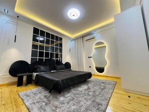 A modern bedroom with a bed, a large window, and a unique wall design.