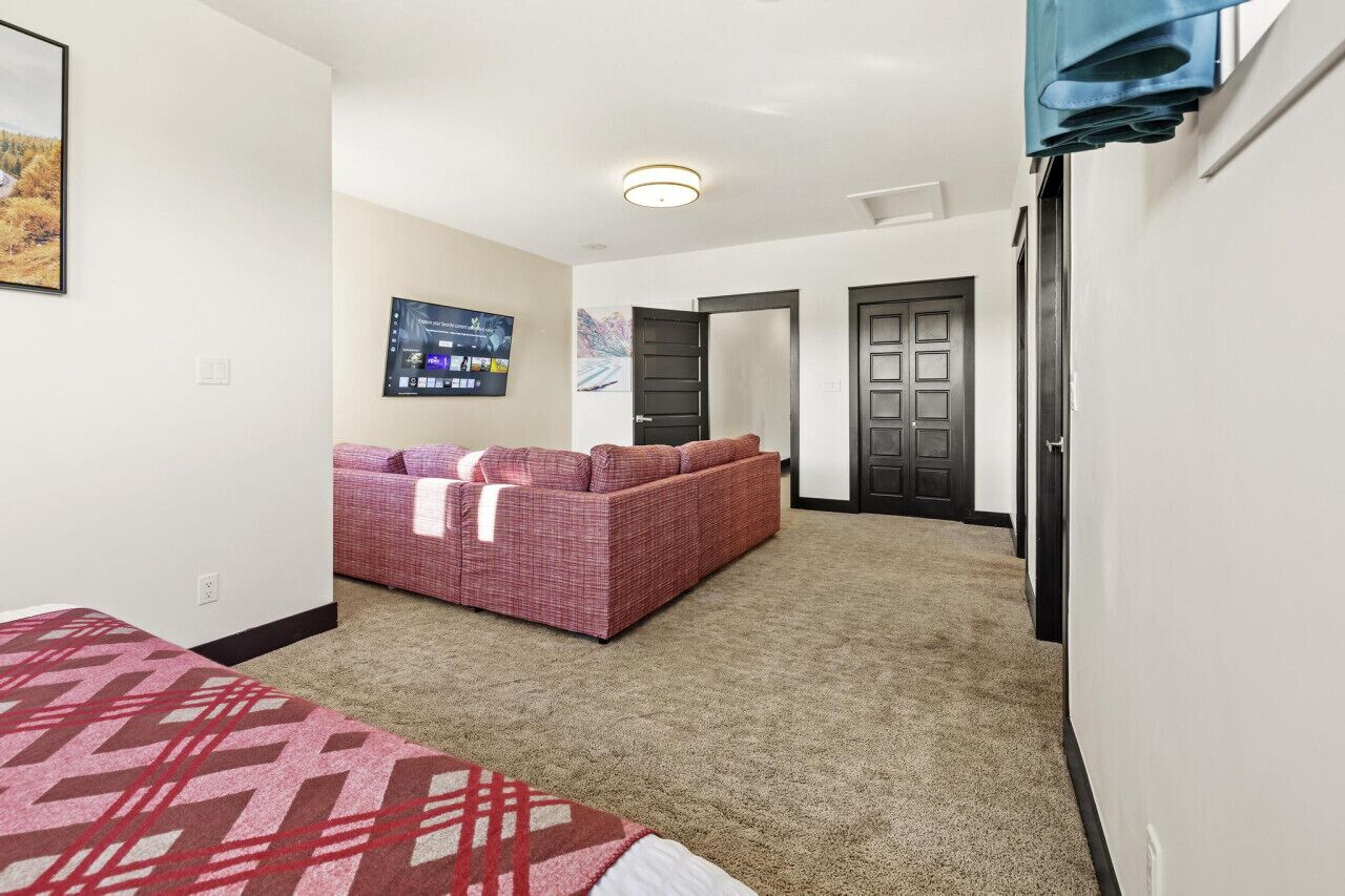 A hotel room with a large bed, a sofa, a TV, and a carpeted floor.