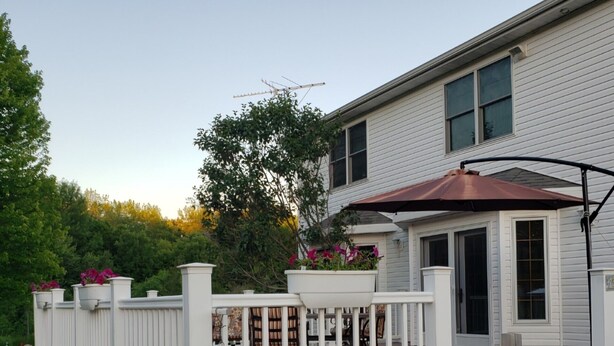 A white house with a covered porch, a white fence, and a black lantern. - Quiet Country Home on 10 acers of land, located only 23 miles from EAA grounds. (Larsen)