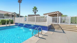 A swimming pool with a white fence, a palm tree, and a covered area with steps. - Newly Renovated Condo Minutes from The Beach, OWA Water Park and Tanger Outlets (Foley)