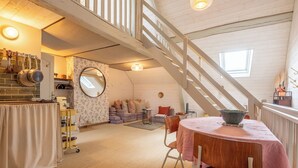 A loft-style room with a staircase, a dining area, and a kitchen. - Cottage de Charme " les Hirondelles " (Samois-sur-Seine)