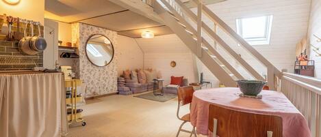A loft-style room with a staircase, a dining area, and a kitchen.