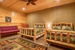 L'interno di una baita di legno con due letti a castello, un divano e un camino.