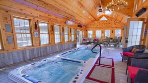 A wooden cabin interior with a hot tub, a dining area, and a fireplace. - Freedom Lodge by Turkey Ridge Lodges (Rockbridge)