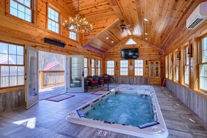 Una baita di legno con vasca idromassaggio, area relax e televisore.