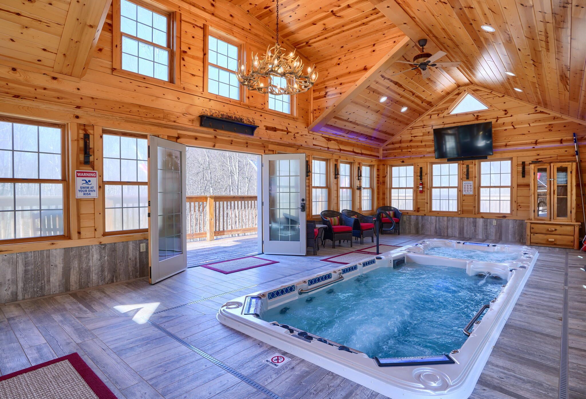 Een houten chalet met een jacuzzi, een televisie en een waarschuwingsbord over het zwemmen.