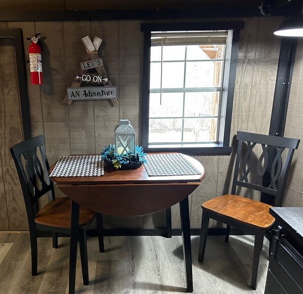 A wooden dining table with two chairs, a lantern, and a sign that reads "LET'S GO ON AN Adventure". - Turkey Ridge Lodges- Cabin 10 (Rockbridge)
