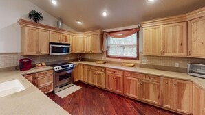 A kitchen with wooden cabinets, a microwave, an oven, and a toaster. - Turkey Ridge Lodges - Lodge # 2 (Rockbridge)