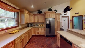 A kitchen with wooden cabinets, a stainless steel refrigerator, a toaster, and a dishwasher. - Turkey Ridge Lodges - Lodge # 2 (Rockbridge)
