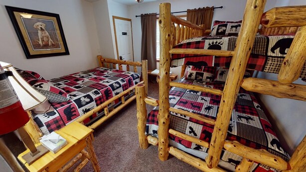 A bunk bed with a quilted blanket, a bedside table with a lamp, and a framed picture on the wall. - Turkey Ridge Lodges - Lodge # 2 (Rockbridge)