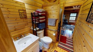 Ein kleines, holzgestaltetes Badezimmer mit Waschbecken, Toilette und Handtuchhalter.