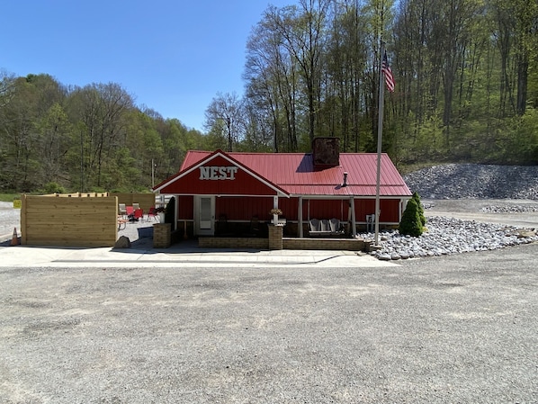 A red building with a sign reading "NEST" in front of a forested area. - Turkey Ridge Lodges - The Nest (ROCKBRIDGE)