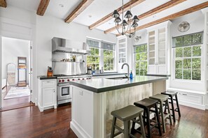 Una cocina amplia con una isla grande, vigas de madera y ventanas espaciosas.