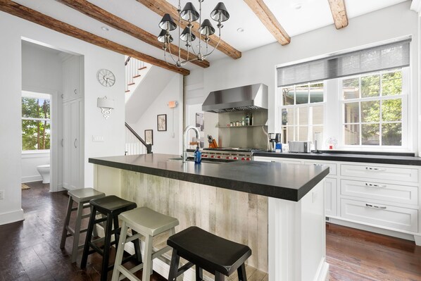 Una cocina moderna con una isla grande, armarios blancos y techo de madera.