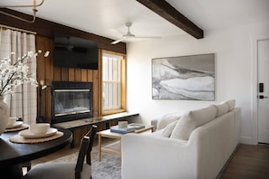 Una sala de estar con chimenea, un sofá, un televisor y un cuadro en la pared.