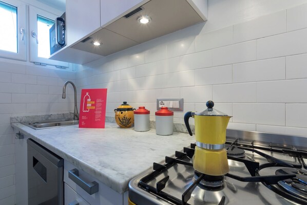 A modern kitchen with white tiles, a gas stove, a coffee maker, and a kettle. - Adriana Family Apartment by Wonderful Italy (Turin)