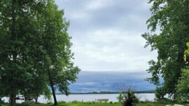 A wooden deck leading to a lake with a bench and trees on either side. - John & Anne`s Place LLC (Litchfield)