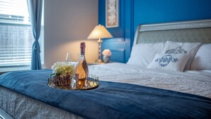 Un lit bien fait, recouvert d’une couvre-lit bleue, un plateau décoratif avec des fleurs et une bouteille, et une lampe en arrière-plan.