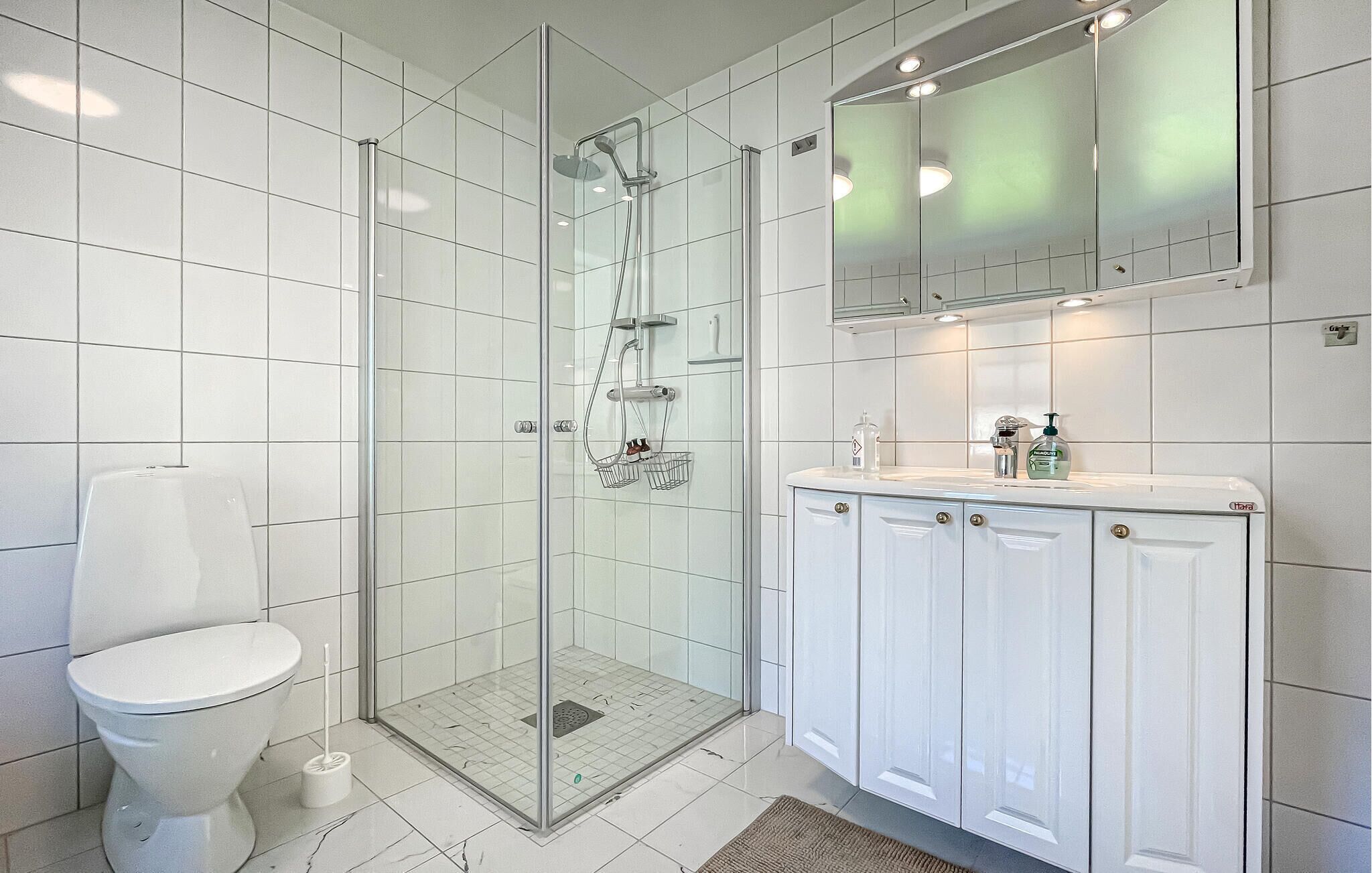 A modern bathroom with a glass-enclosed shower, a toilet, and a vanity with cabinets.