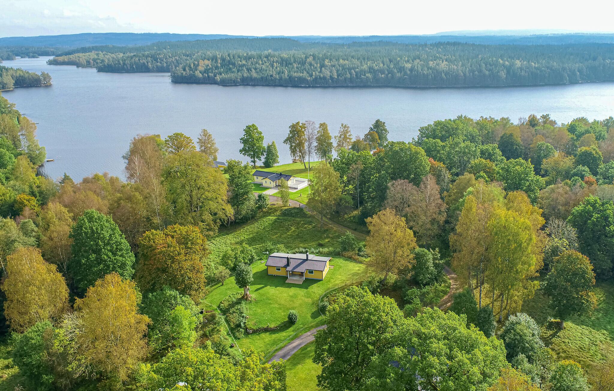 A lakeside property with a house surrounded by lush greenery and a view of the lake.